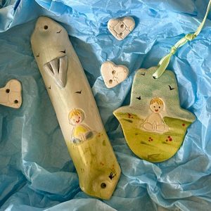 סט חמסה ומזוזות קרמי בעבודת יד זה הוא תוספת מקסימה ומשמעותית לכל חדר ילדים. סט יודאיקה זה, המצויר ביד, נוצר בקפידה בסטודיו שלי בנגב, וכולל איור מקסים של ילדה מתוקה המביאה חום, שמחה והגנה לחדר הילדים שלכם. סט יודאיקה זה לחדר ילדים הוא מתנה אידיאלית לתינוק, מתנה למסיבת לידה או מתנה לחנוכת בית יהודית להורים חדשים. החמסה באורך של כ-8 ס"מ ורוחב של כ-8 ס"מ בית המזוזה בערך: 4 ס"מ x 18 ס"מ סט בית מזוזה וחמסה מקרמיקה בעבודת יד לחדר ילדים  סטודיו בר